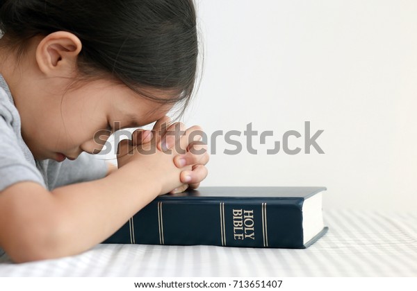 Asian girl hands with Bible praying, Hands folded in prayer on a Holy Bible. 