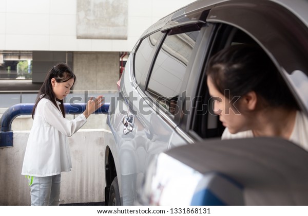 Asian girl help waving a car for\
her mother to reverse in parking car,her mother drove\
carefully
