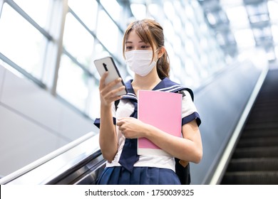 Asian Girl High School Student Take Escalator In The Mrt Station With Facial Mask And Use Mobile Phone