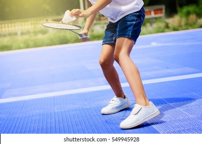 Asian girl holding badminton racket and shuttlecock at court