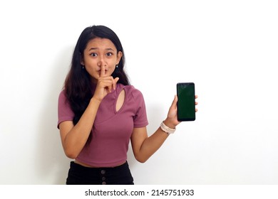 Asian Girl Holding Cellphone With Silent Gesture. Isolated On White Background