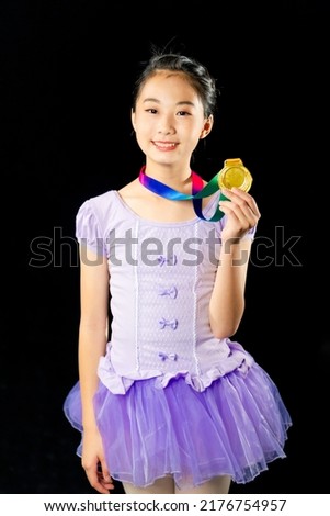 Asian girl holding a gold medal. Figure skater. Ballet dancer.