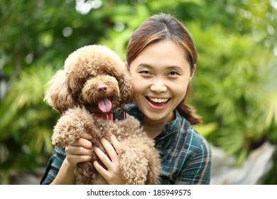 Asian Girl Hug With Her Poodle Dog In The Garden.