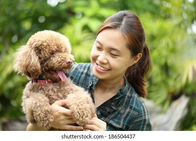 Asian girl hug with her poodle dog in the garden