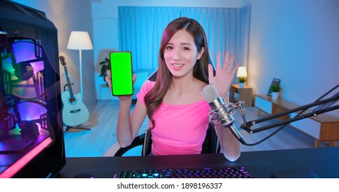 Asian Girl Internet Celebrity Say Hello To Her Fans In A Live Stream And Show App On The Smartphone With Green Screen At Home