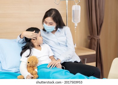 Asian girl kid get accident to fracture broken arm sleep lying in hospital bed with teddy bear and talking with mum. Asia Mother take care and play with cute little girl before get treat from doctor.