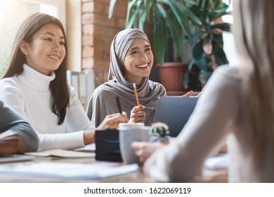 Asian Girl And Lady In Hijab Smiling During Business Meeting In Office, Close Up