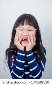 Asian Girl Laughing And Being Goofy Showing His Lost Teeth.