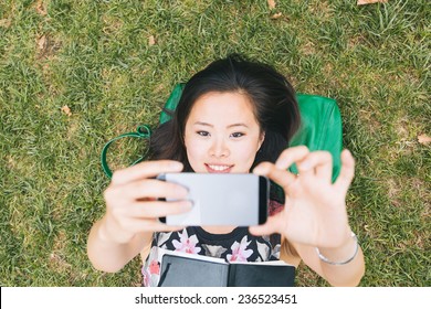 Asian Girl Laying Down on the Grass and Taking Selfie