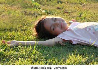  Asian girl lie down on grasses or lawn under warm sunlight.Girl closed her eyes and flew away.Relaxing and happy.Image with rim light 