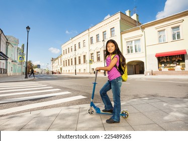 Asian girl with long hair stands on scooter - Powered by Shutterstock