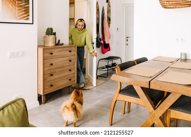 Asian Girl Looking At Her Dog While Walking Through Door At Home