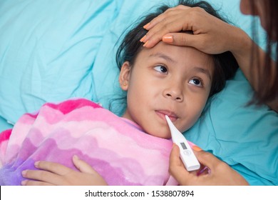 An Asian Girl Is Looking Her Mother And Hand Holding A Thermometer To The Mouth. May Have A Cough Until Sore Throat, Difficulty Swallowing, Colds, Flu Or Fever, Meet A Doctor At The Hospital