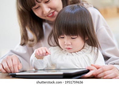 Asian Girl Looking At A Tablet With Mom