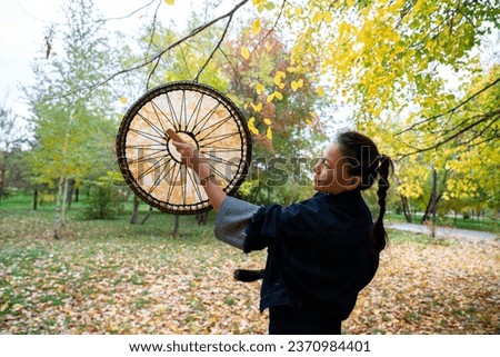 An Asian girl in modern clothes with a shamanic tambourine in her hands. High quality photo