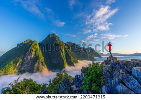 Asian girl on top Viewpoint of Nong Khiaw - a secret village in Laos. Stunning scenery of limestone cliff valley covered with fog