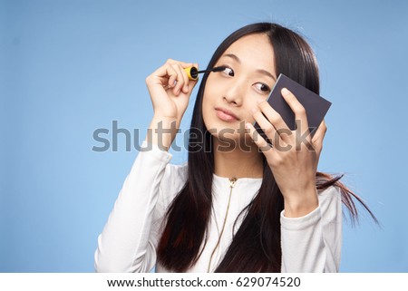     Asian girl paints eyelashes with mascara