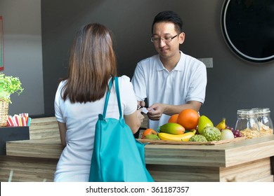 Asian Girl Paying Bills  For Grocery To Sales Man