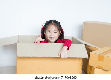 Asian Girl Playing In The Box At Home. Kid Sitting Inside Box With Attractive Smiling.