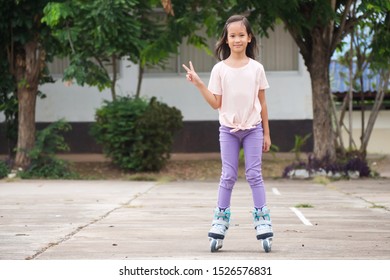 Asian girl playing rollerblade. Outdoor activity. Standing with show 2 fingers in Victory sign. Sport background with copy space. - Shutterstock ID 1526576831