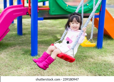 Asian Girl Playing Swing At Playground