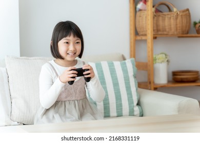 Asian Girl Playing Video Game In The Living Room