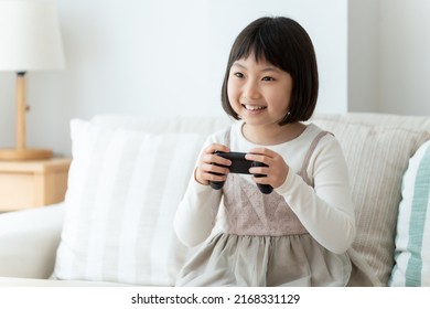 Asian Girl Playing Video Game In The Living Room