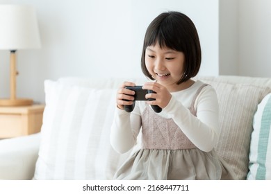 Asian Girl Playing Video Game In The Living Room