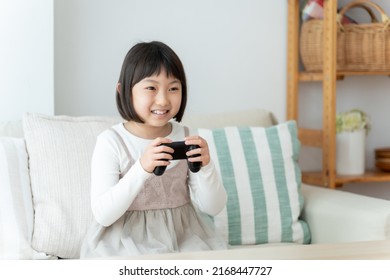 Asian Girl Playing Video Game In The Living Room