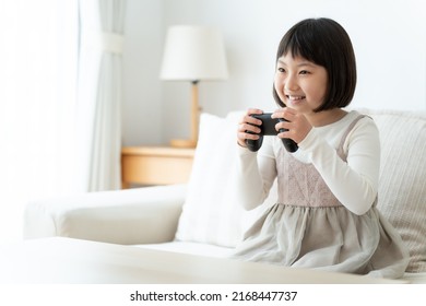 Asian Girl Playing Video Game In The Living Room