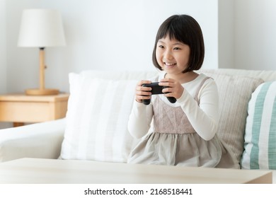 Asian Girl Playing Video Game In The Living Room