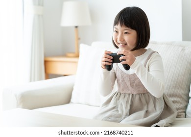 Asian Girl Playing Video Game In The Living Room