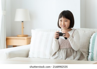 Asian Girl Playing Video Game In The Living Room