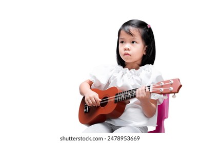 Asian girl practicing playing ukulele with intent expression. Learning music and sheet music. Isolated background. - Powered by Shutterstock