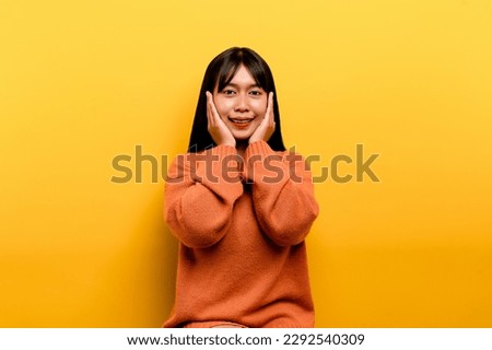 asian girl Pretty wearing an orange casual dress. yellow background Celebrate the victory with a happy smile and the winner's expression with a raised hand. happy expression