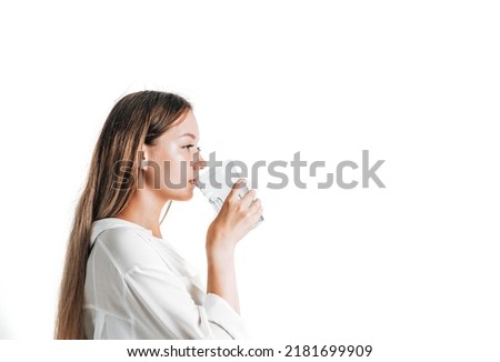 Asian girl with purple drinks water from a plastic bottle on a white isolated background. Generation Z. The concept of thirst