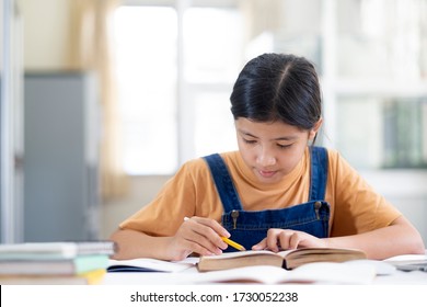 Asian Girl Reading And Doing Homework At Her Home. Education And Self Learning Concept. 