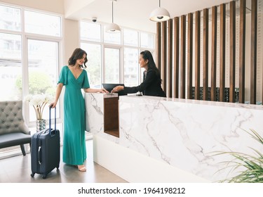 Asian girl receptionist and Caucasian woman traveler checking or checkout in hotel