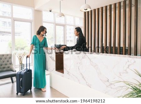 Asian girl receptionist and Caucasian woman traveler checking or checkout in hotel