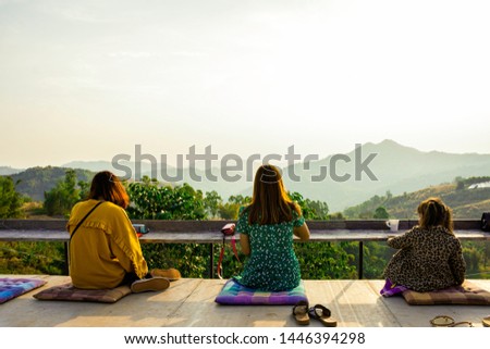 Asian girl relax with landscape nature mountain in the morning, Sit on balcany looking beautiful sunrise on the peak of mountain, Asian women wear jacket in winter with green nature view