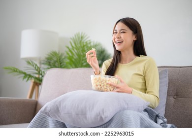 Asian girl relaxing at home Enjoying Watching Television with glass bowl of popcorn. - Powered by Shutterstock