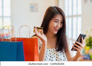 Asian Girl Shopping Online Happily.A Multicolored Paper Bag Placed Next To It.