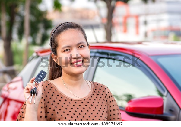 Asian girl showing the car\
key. 