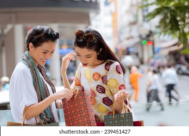 Asian Girl Showing Something In The Shopping Bag To Her Friend