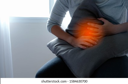 Asian Girl Sit And Hold Hand At Stomach Ache Like Symptoms Specific To Indigestion, Abdominal Pain This Area, Maybe Menstrual Pain Or A Period Cramps, Go To The Hospital See A Doctor Or First Aid Asap