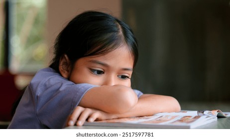 An Asian girl sits at a table in a library, her face clearly showing boredom as she looks away from the open book in front of her. She looks disinterested and lost in thought. - Powered by Shutterstock