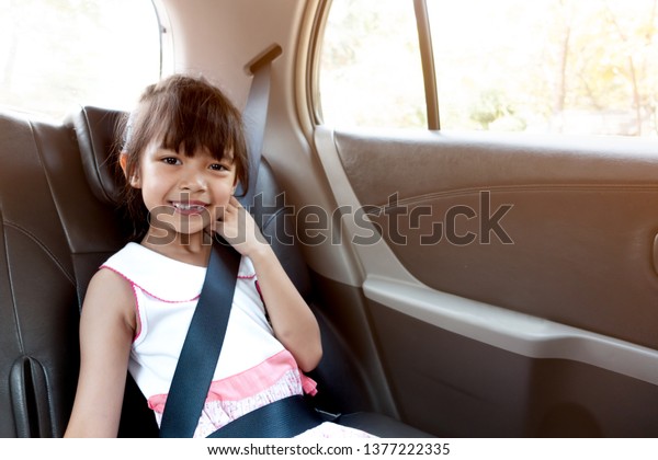 Asian girl sitting in the car with safety belt.\
Safety rule for baby is to tide the safety belt. Happy girl in the\
car with sun light\
shading.