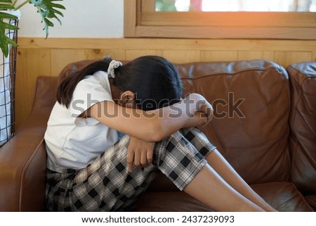 Asian girl sitting hugging her knees, face down, crying on the sofa When something affects the mind, it shows emotions of sadness, sadness, stress, dissatisfaction, likes to be alone and depressed.   