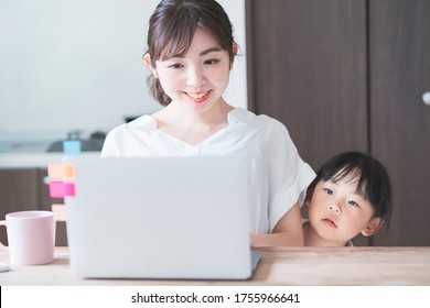 Asian girl snuggling up to mom teleworking at home