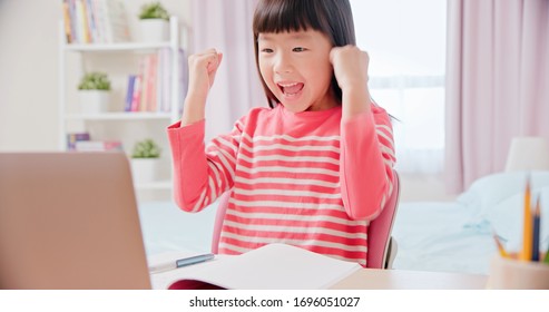 Asian girl student feel very excited and use laptop to have online class happily at home